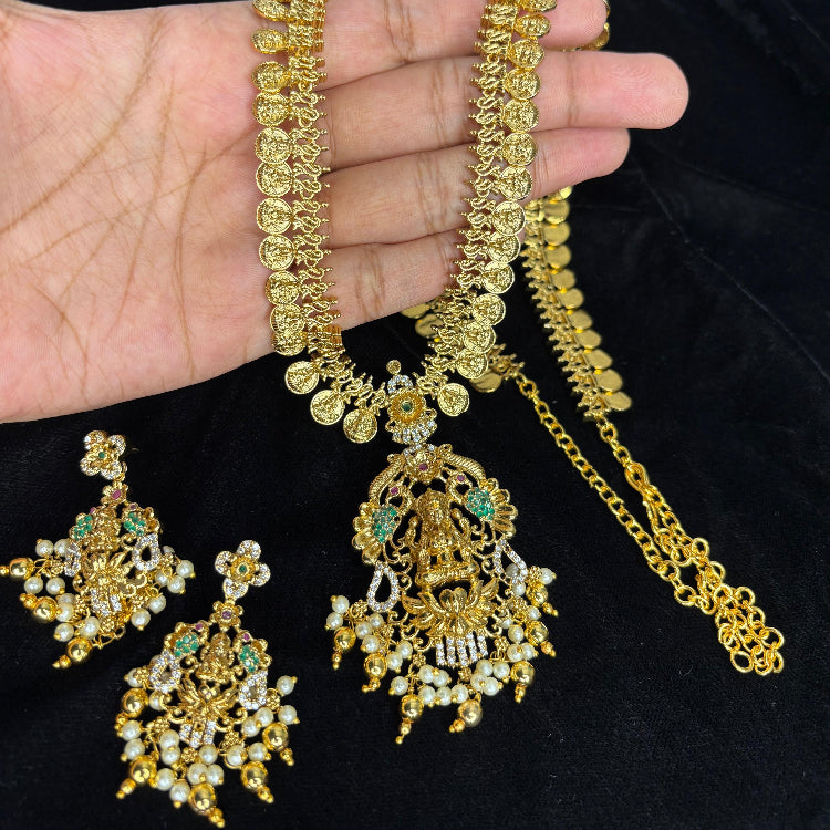 Gold jewelry set including necklace, earrings, and ring on a hand against a black background