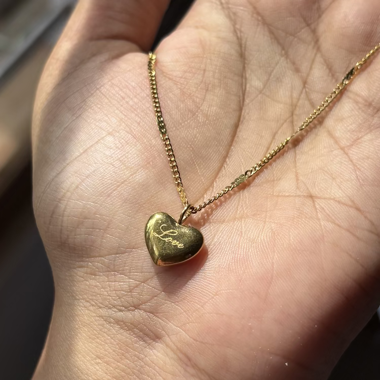 Gold heart-shaped pendant necklace on a hand