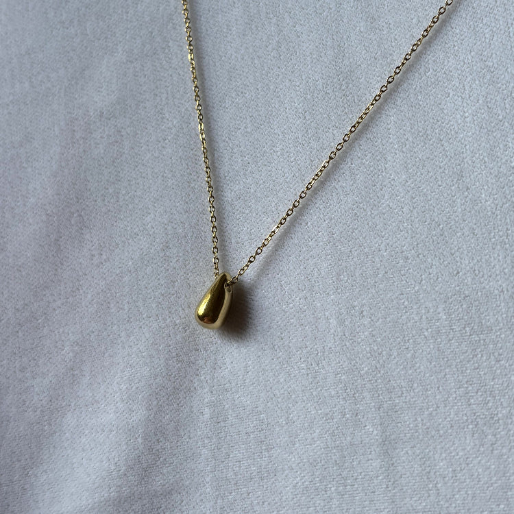 Gold necklace on a light gray background
